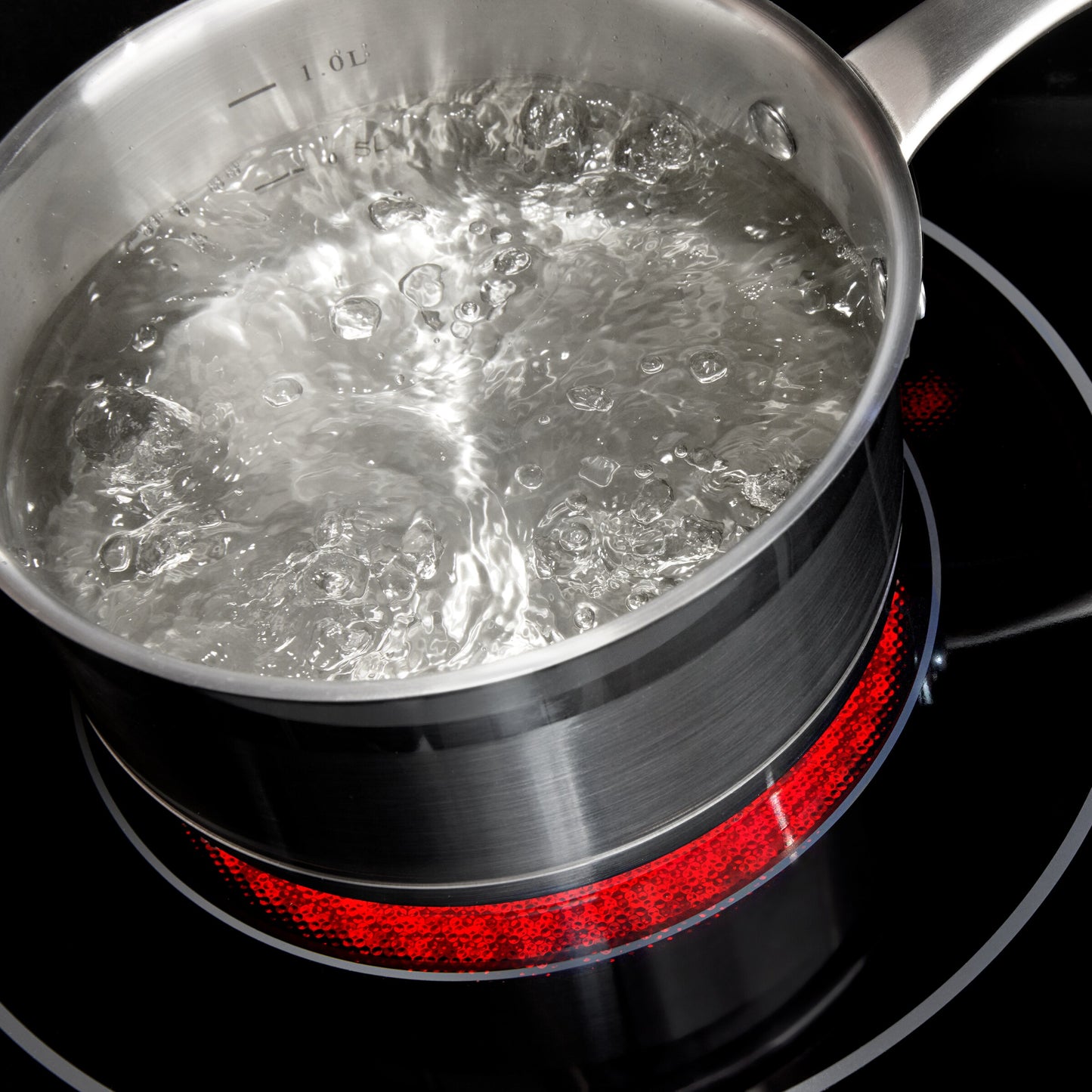 Stainless steel pot with boiling water on a 30-inch electric range cooktop heating element glowing red