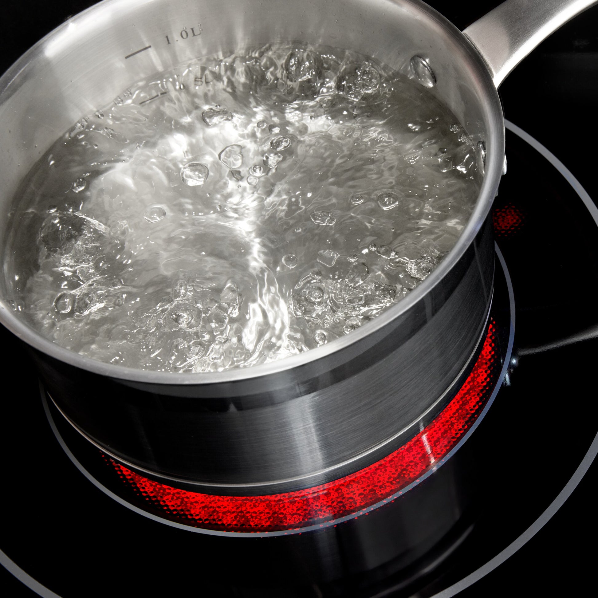 Stainless steel pot with boiling water on a 30-inch electric range cooktop heating element glowing red