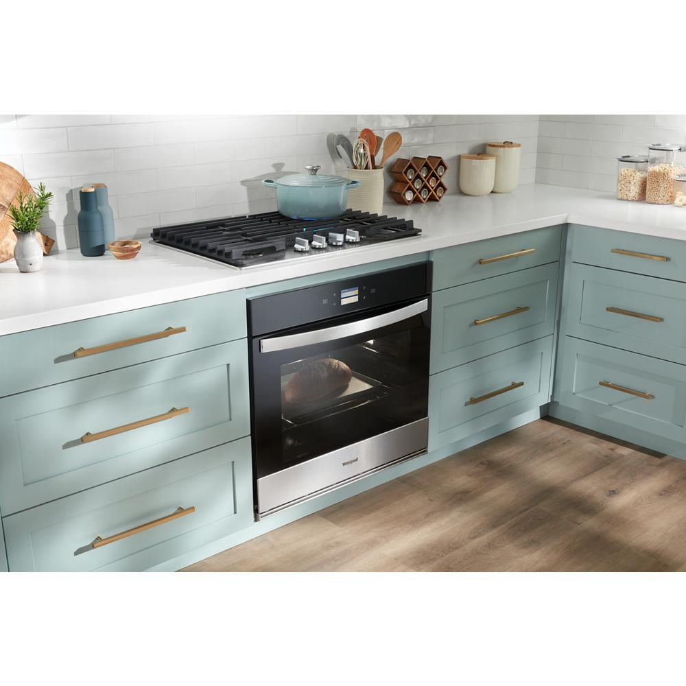 Modern kitchen featuring a stainless steel built-in oven below a gas cooktop with cast-iron grates in teal cabinetry