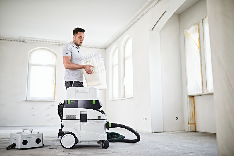 Man installs clear plastic dust collector on white Festool CT-VA-20 cyclone separator for dust management in woodworking tools collection