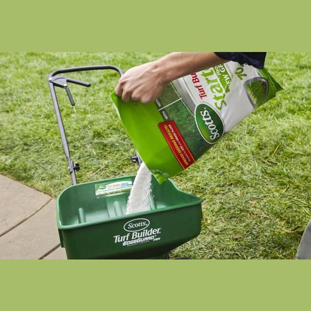 Person pouring starter fertilizer into green Scotts spreader on lawn lawn and garden plant care collections