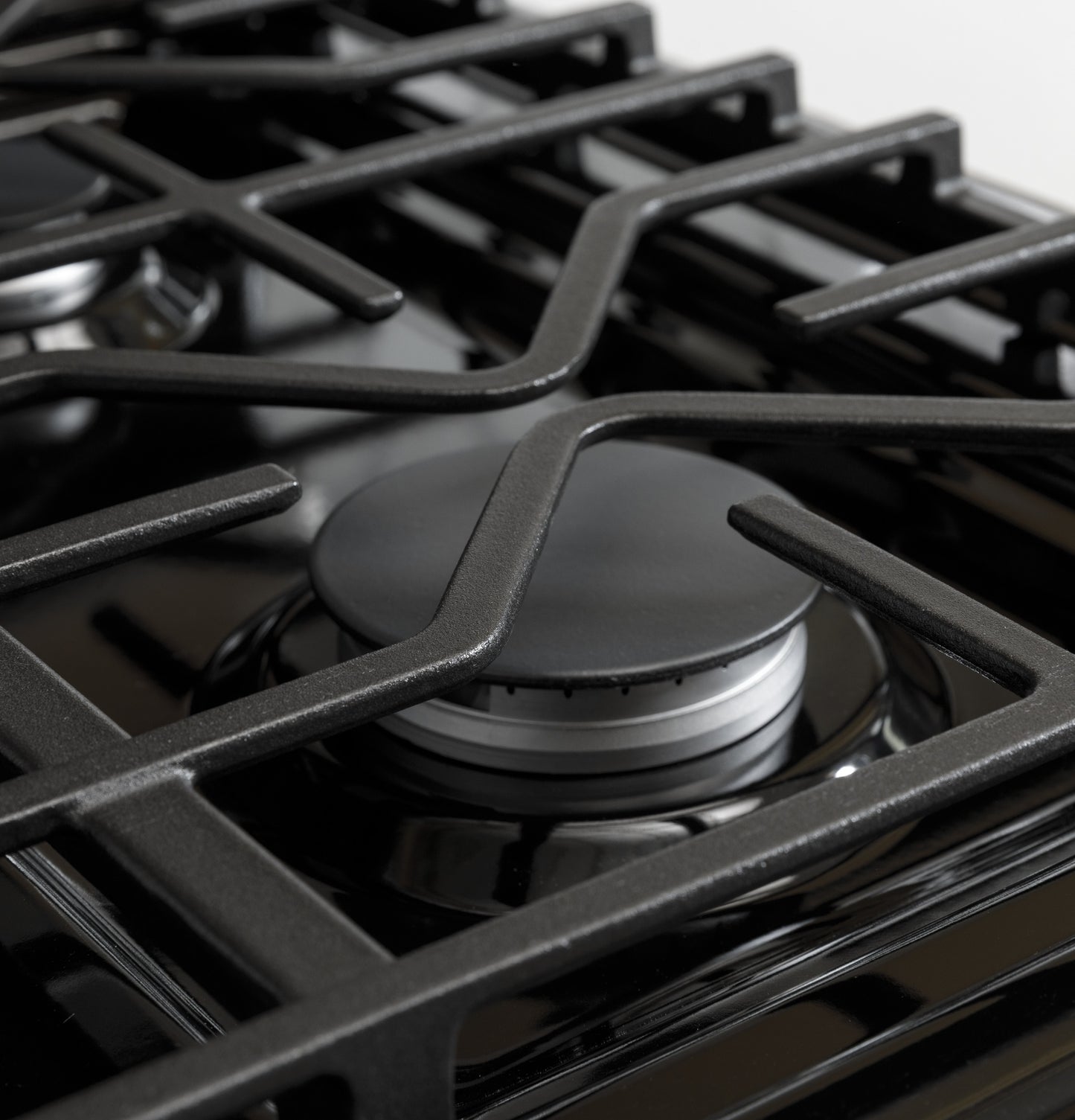 Close-up of matte black gas burner with sturdy grates on range from kitchen appliances collection.