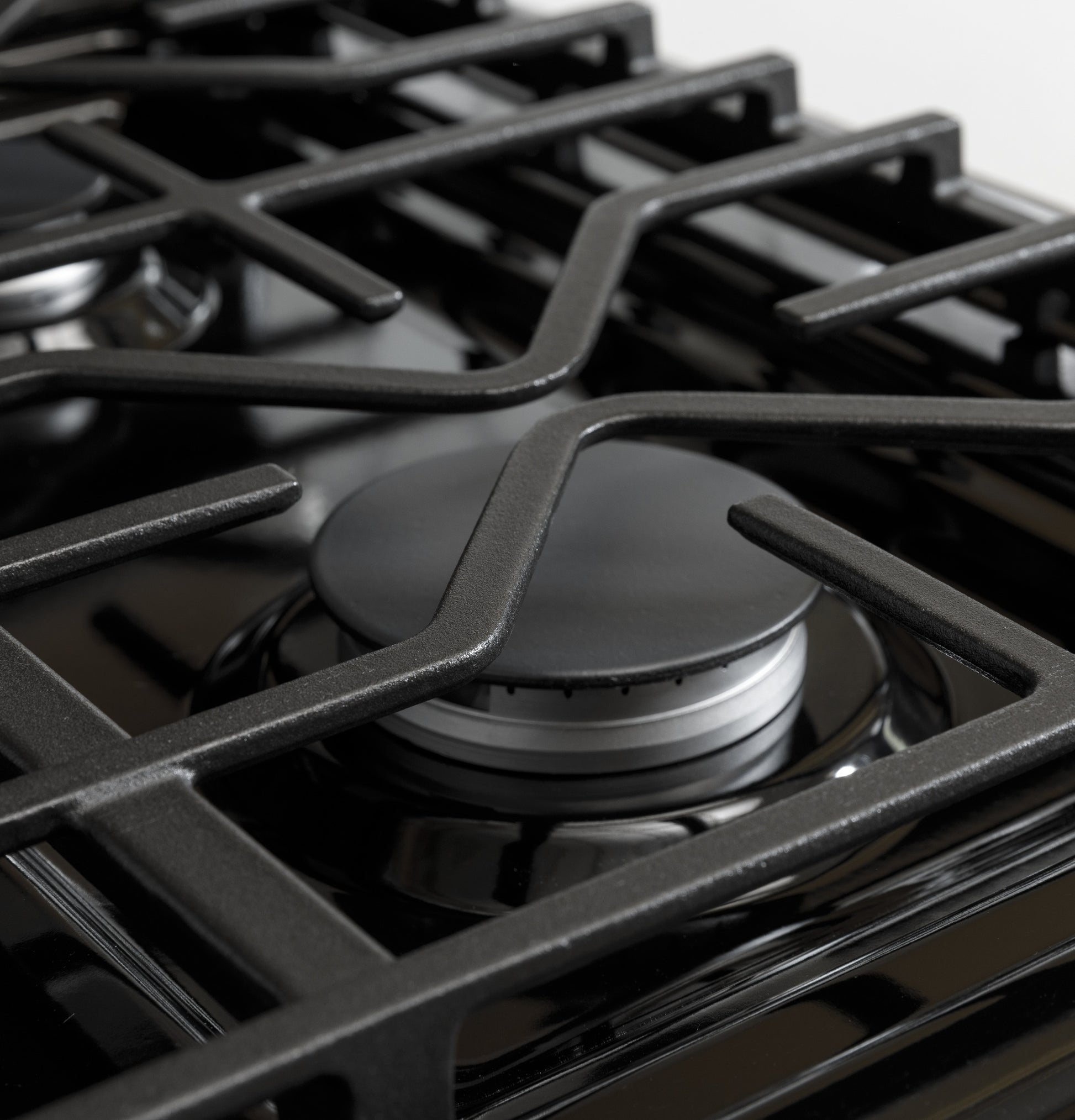 Close-up of matte black gas burner with sturdy grates on range from kitchen appliances collection.