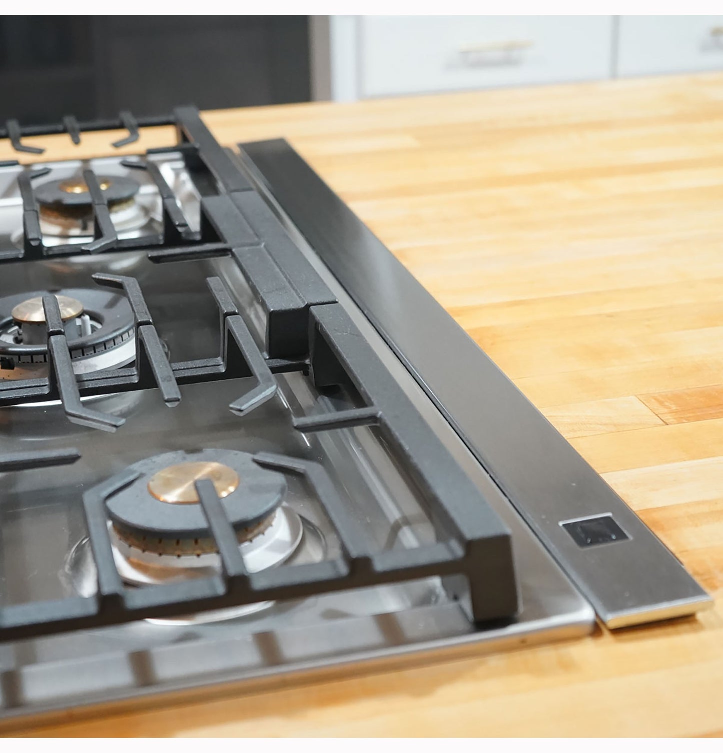 Black telescopic downdraft vent integrated beside stainless steel gas cooktop on wooden countertop in kitchen appliances collection