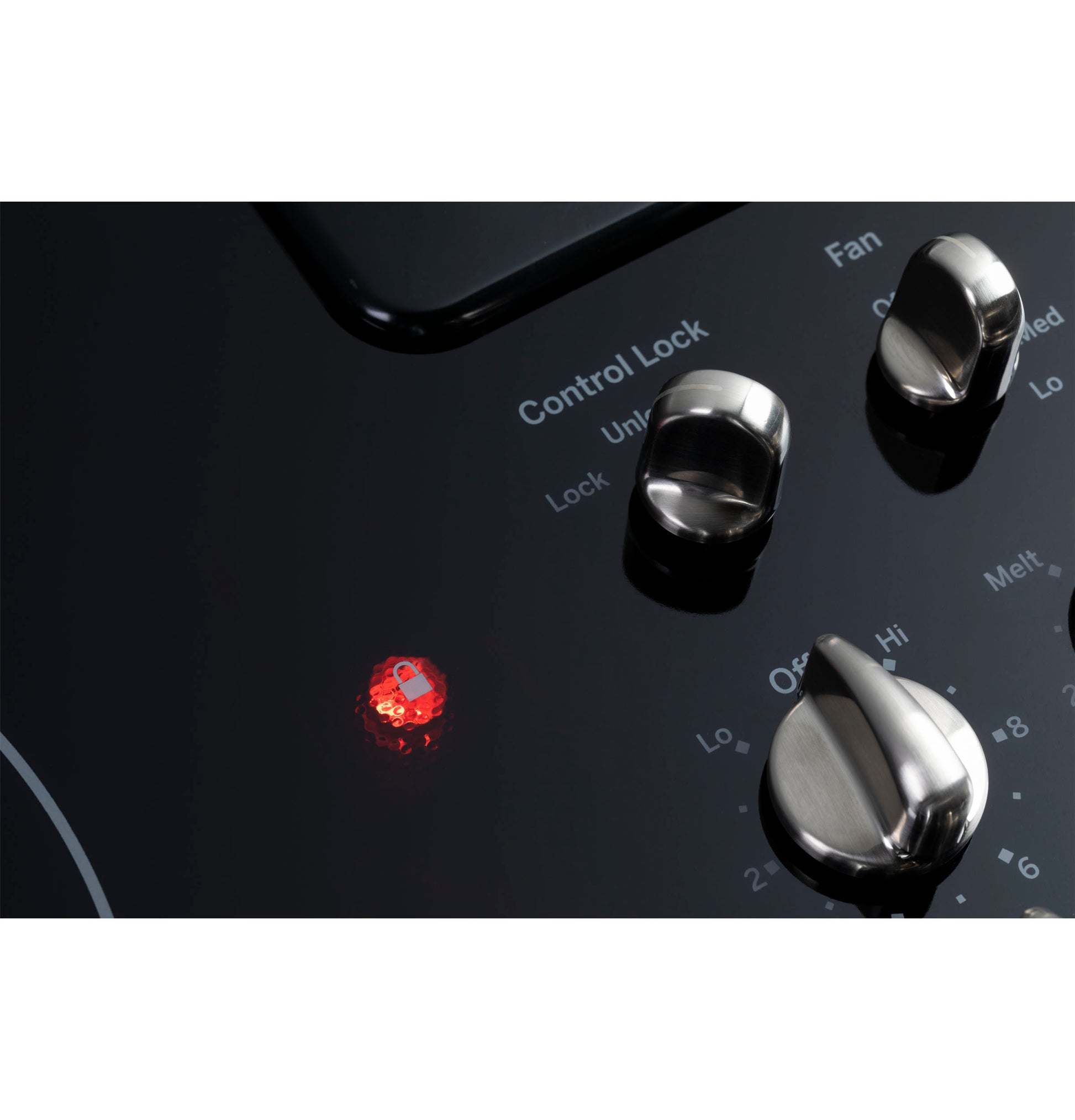 Close-up of GE Profile downdraft cooktop control knobs with illuminated control lock indicator in kitchen appliances collection