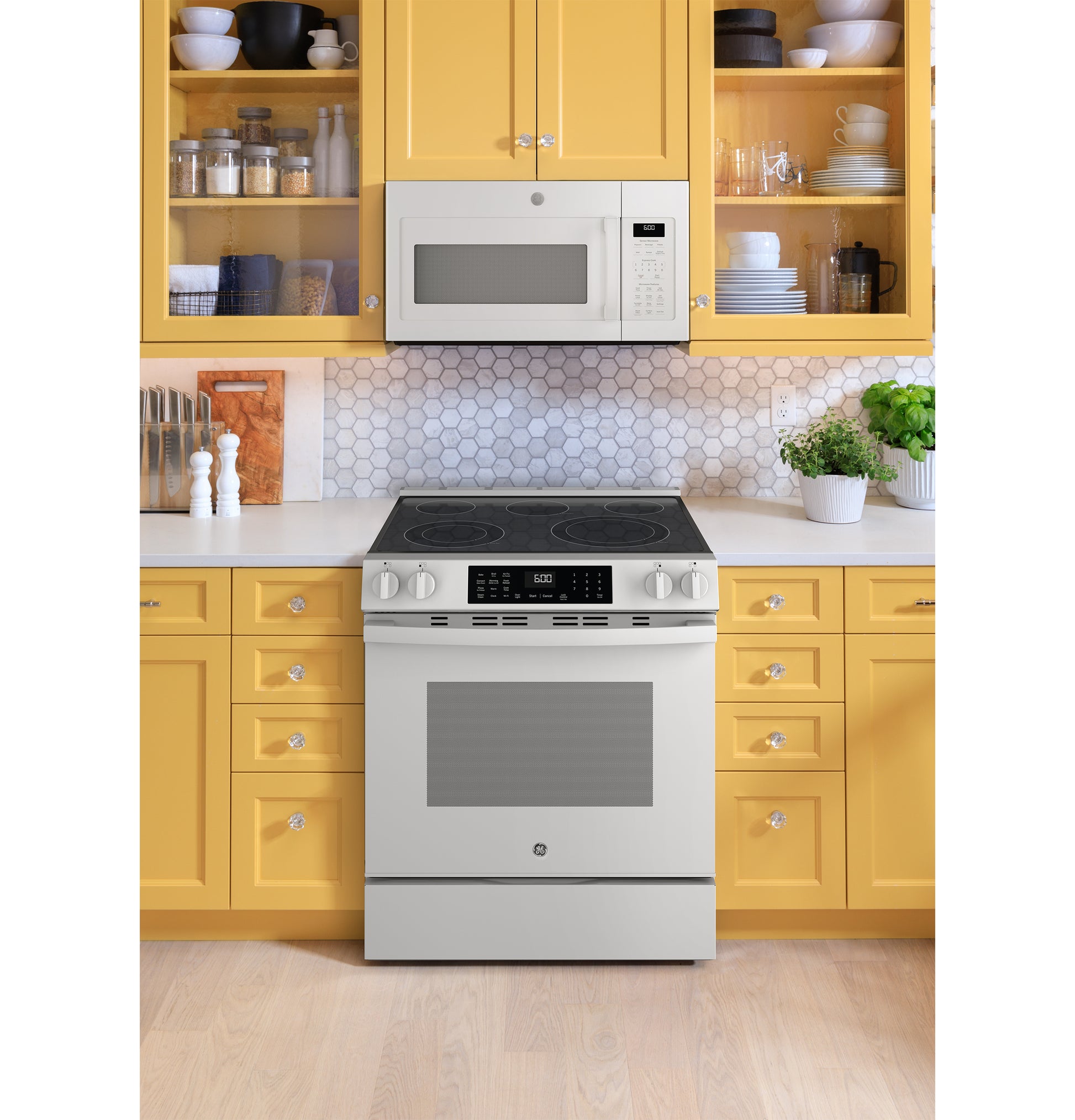 White slide-in electric convection range with digital controls and smooth cooktop in kitchen with yellow cabinetry