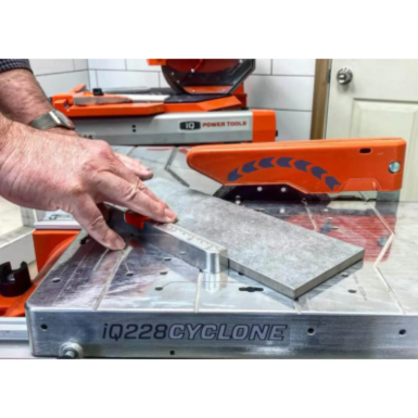 Person using iQ Power Tools tabletop tile saw with blade guard and angle-adjustable fence for home improvement tools collection