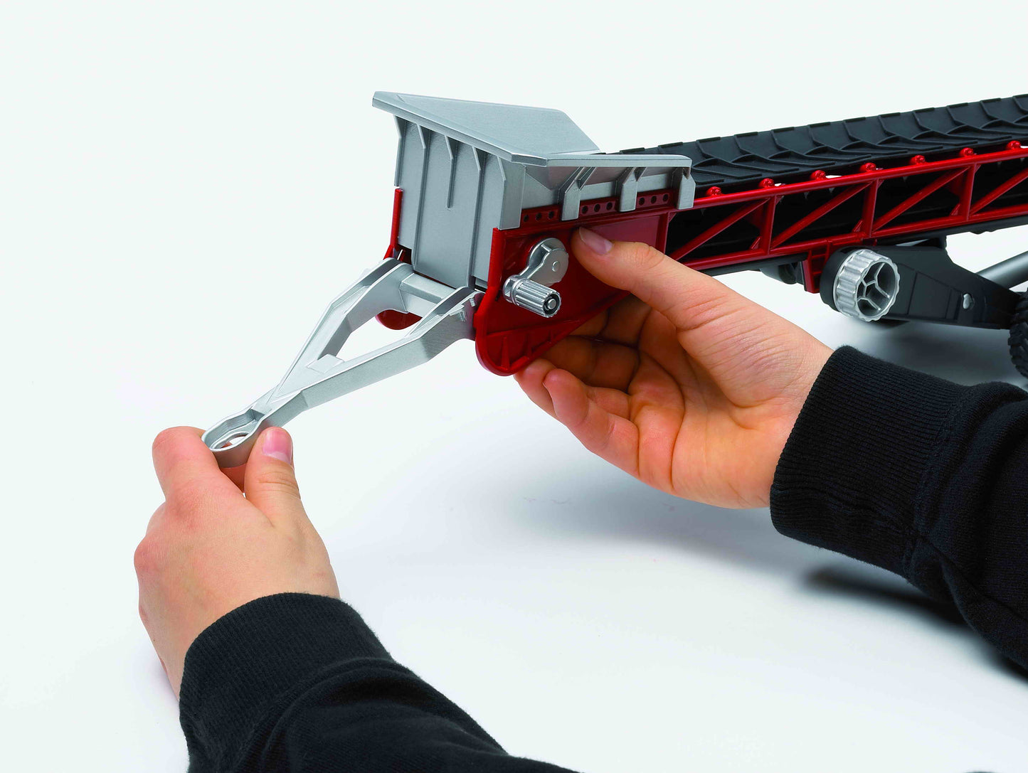 Child's hands adjusting red and gray toy conveyor belt with hand crank in Bruder Toys and Vehicles collections
