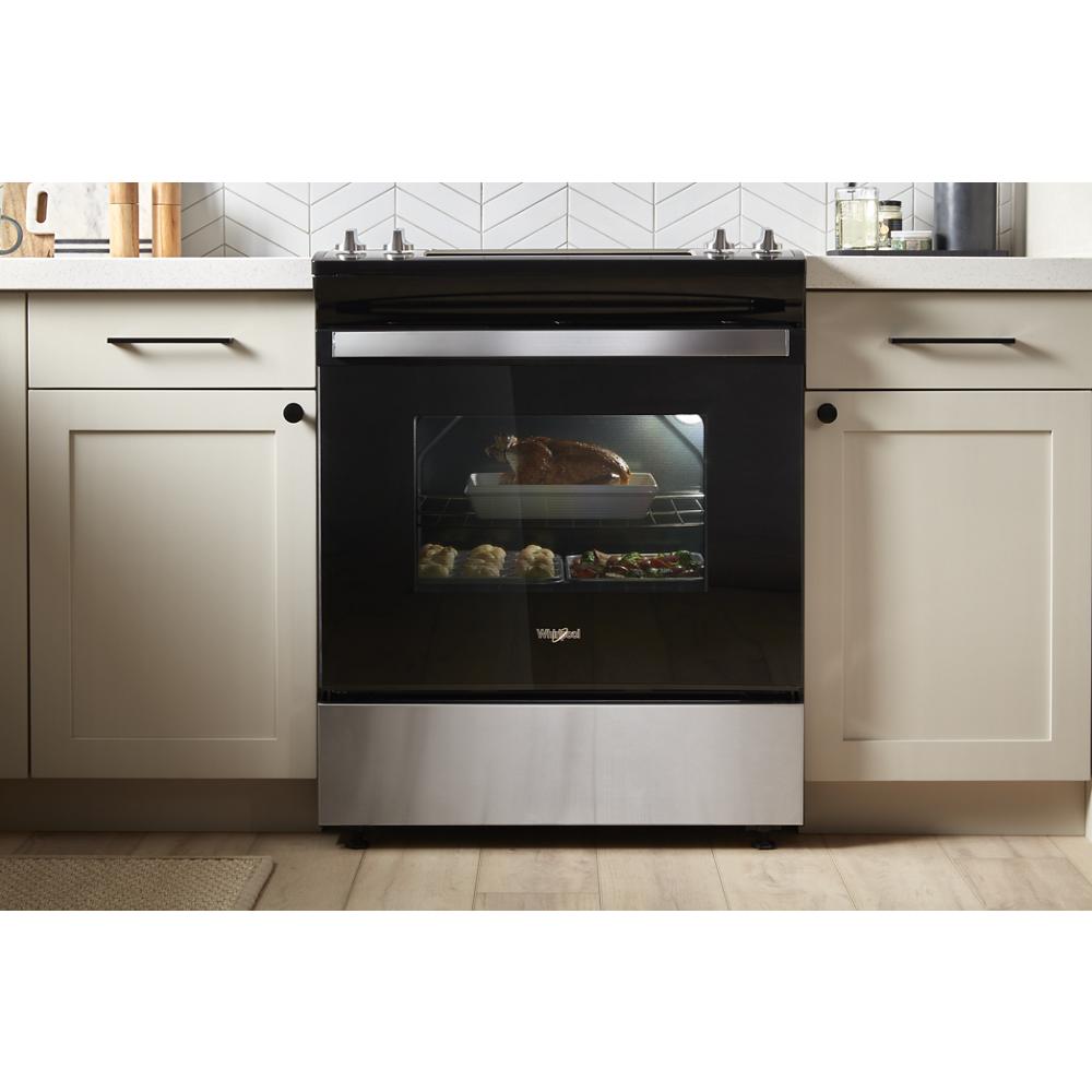 Black and stainless steel electric slide-in oven with food baking inside in modern kitchen setting