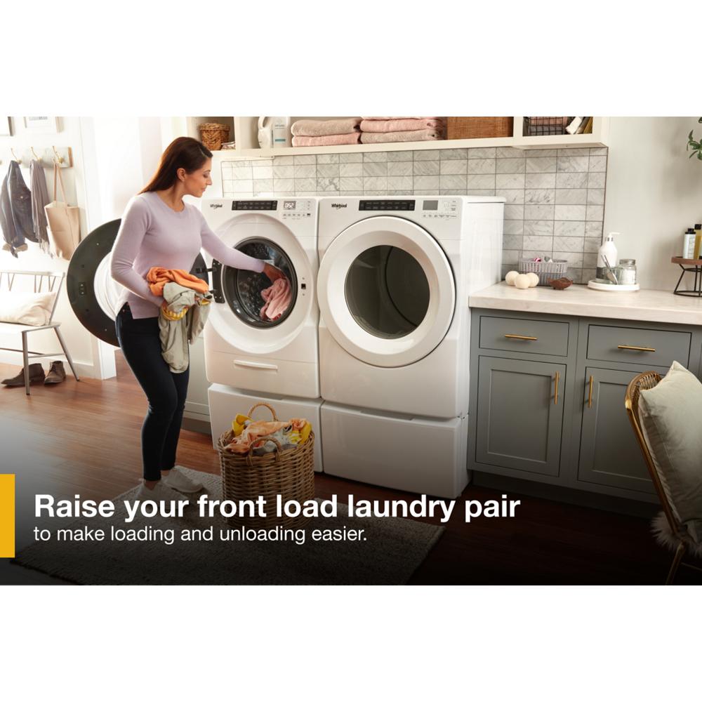 Woman loading clothes into a white front load washer elevated on a storage pedestal in a modern laundry room setting