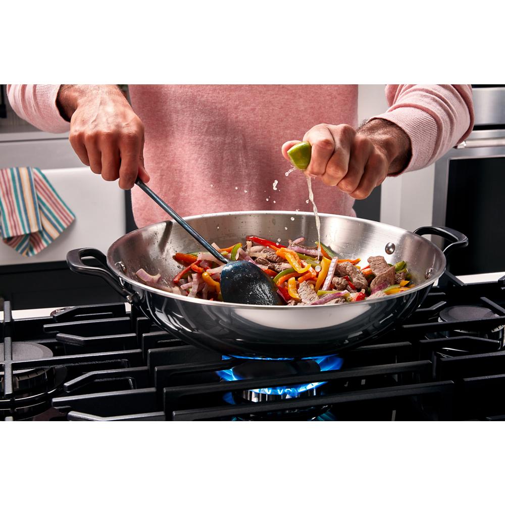 Wok on gas burner stir-frying colorful vegetables and beef with lime juice being squeezed for home improvement tools