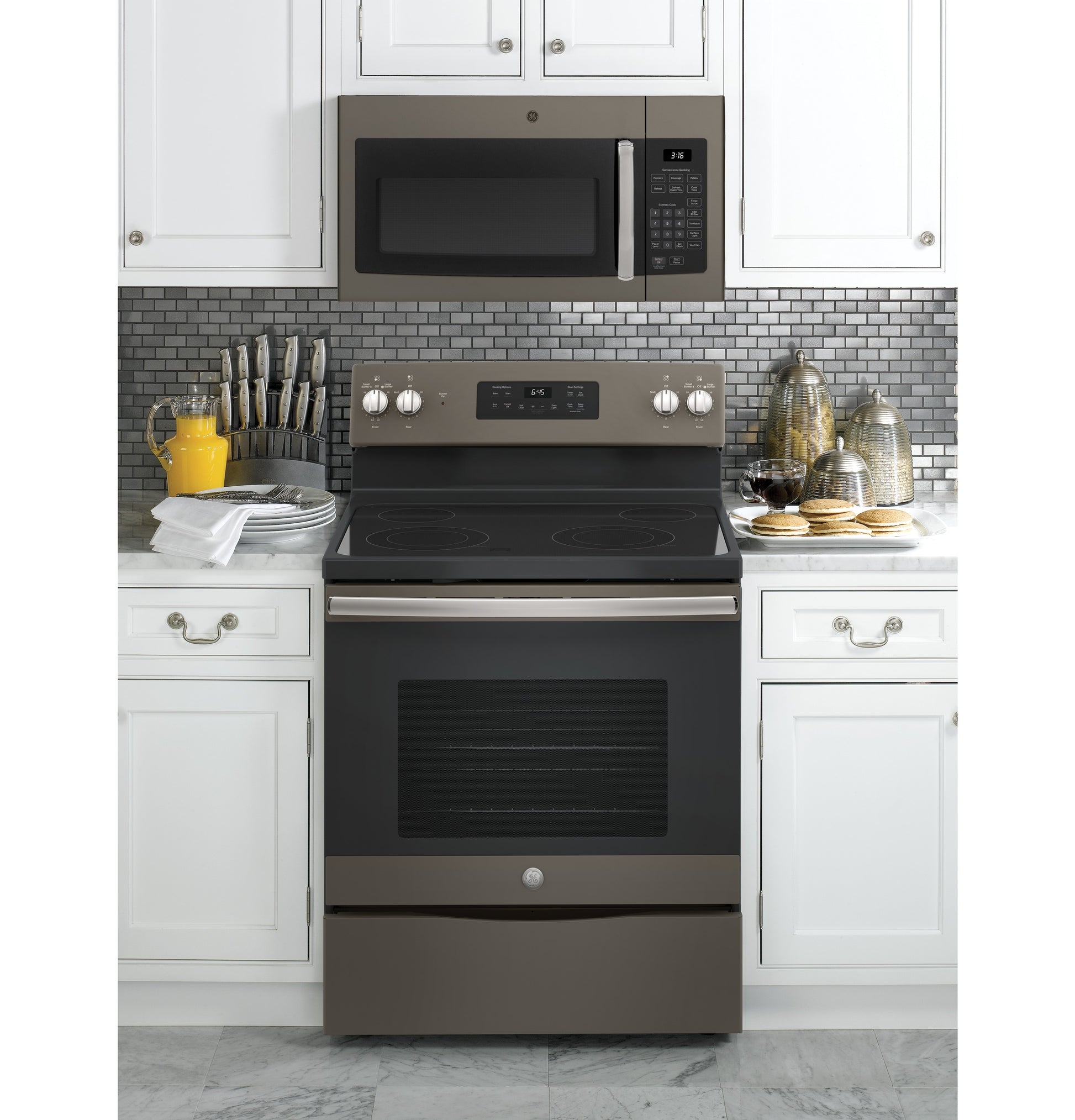 GE® 1.6 Cu. Ft. over-the-range microwave in stainless steel installed above matching electric range in modern kitchen setting