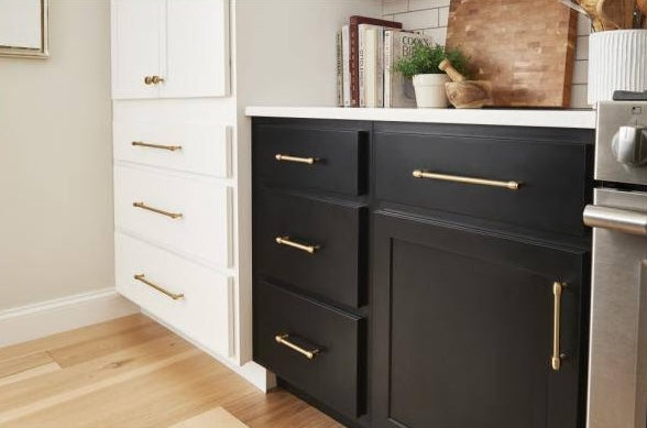 Polished nickel cabinet bar pulls on black and white kitchen cabinetry in modern home improvement setting