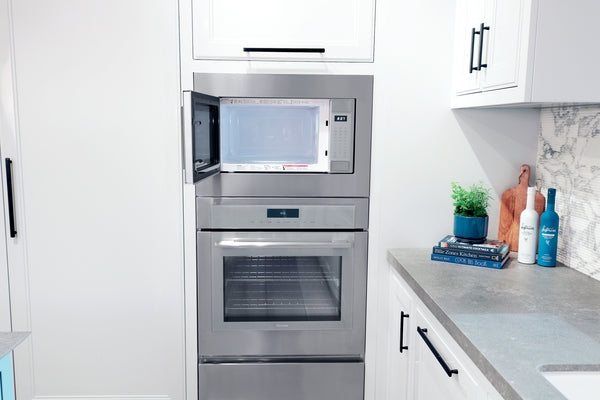 Thermador stainless steel built-in microwave with left side door opening above built-in oven in modern kitchen setting