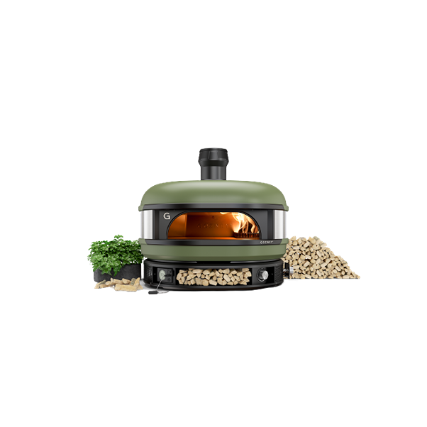 Outdoor olive-green dome pizza oven with visible flame, wood storage, and fresh herbs for home improvement use