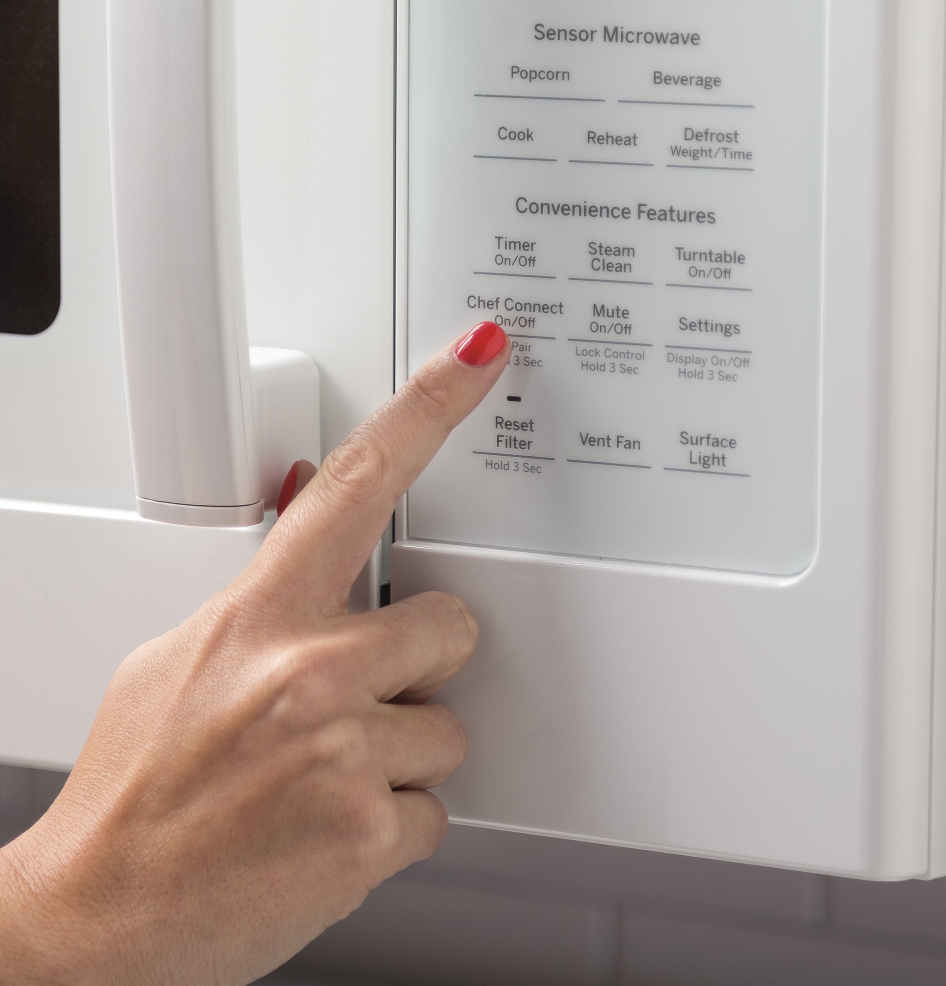 Close-up of hand pressing control panel button on white convection microwave from kitchen appliances collection