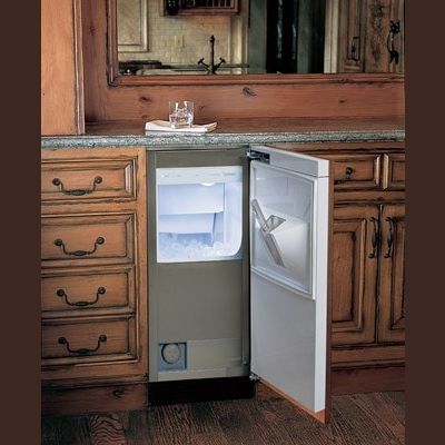 Built-in ice maker with pump inside wooden cabinetry, open door revealing ice compartment for home improvement use