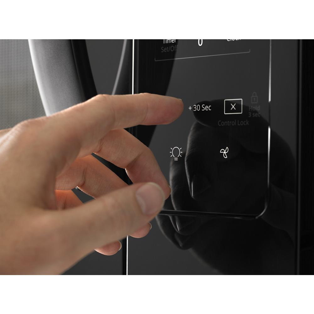 Hand interacting with electronic touch controls on black over-the-range microwave from appliances collection