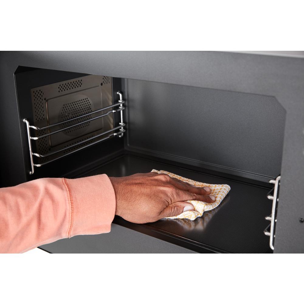 Hand wiping interior surface of air fry over-the-range oven, part of kitchen and appliances collection