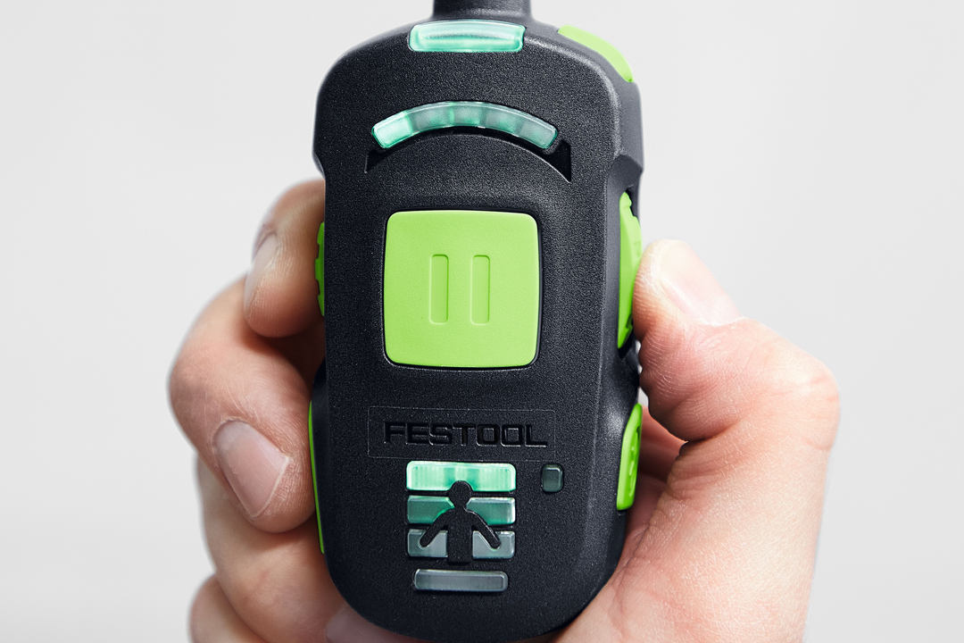 Close-up of hand holding a compact Festool tool accessory with ergonomic control buttons and indicator lights