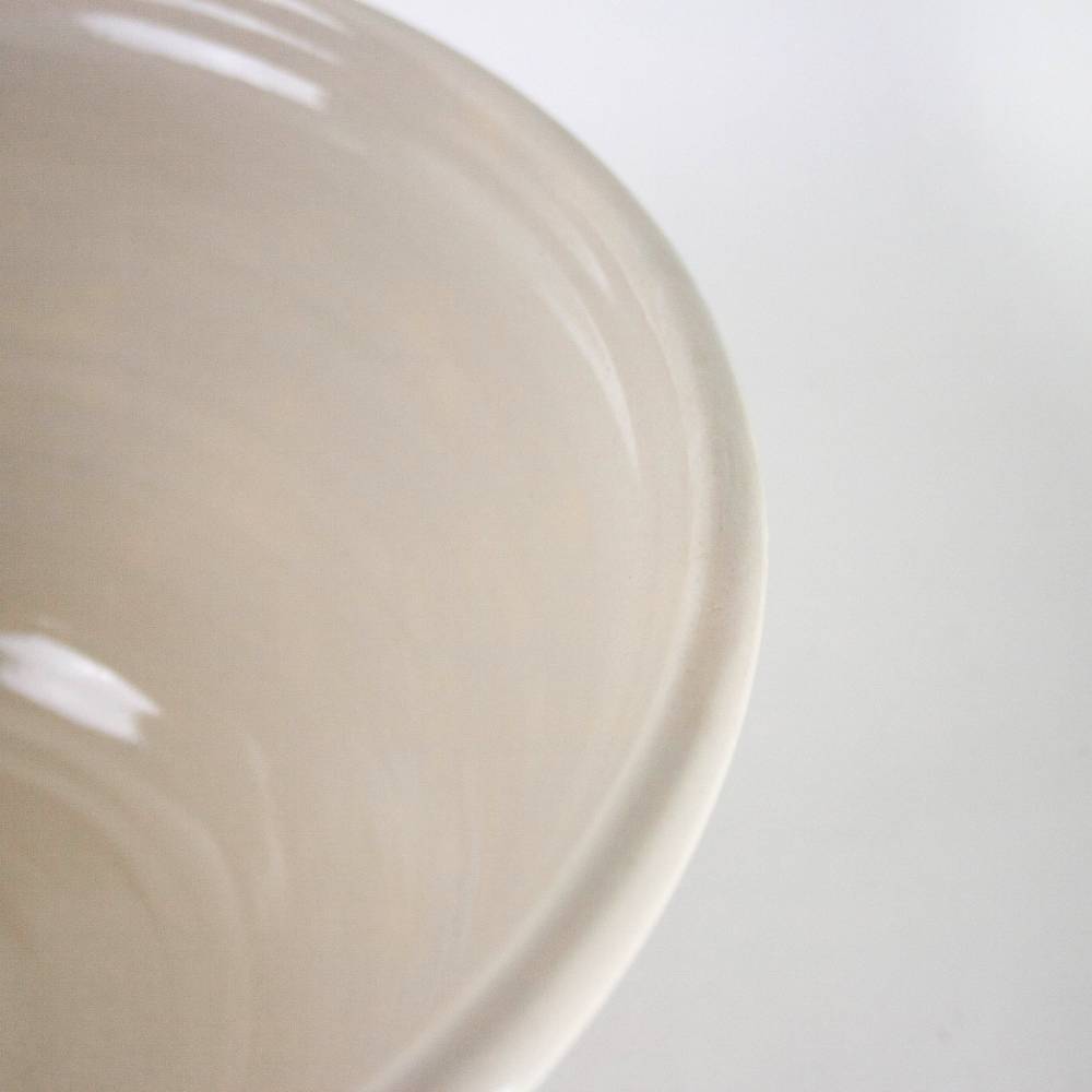 Close-up view of a cream-colored stoneware mixing bowl with smooth glaze in kitchenware collections under $100
