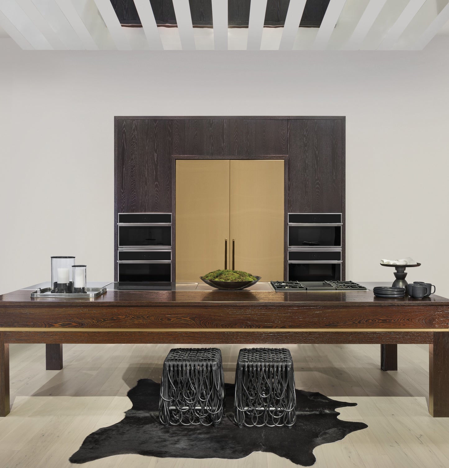 Contemporary kitchen with built-in wall ovens, dark cabinetry, brass refrigerator, and large wooden island in appliances collection