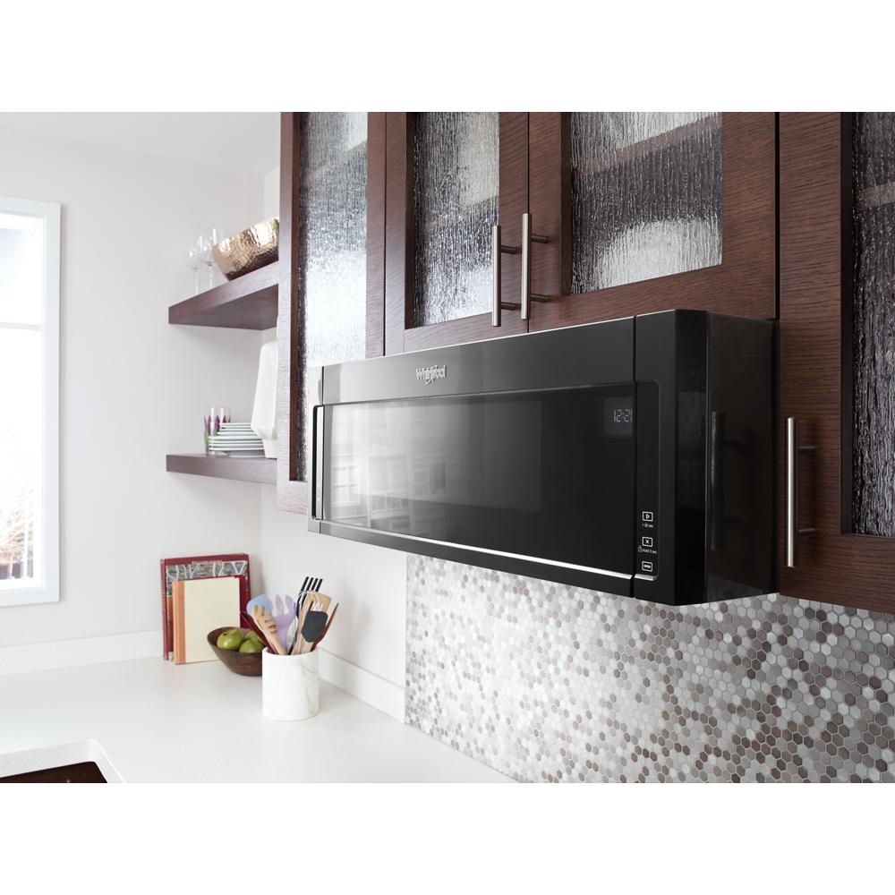Black low profile over-the-range microwave installed above a countertop with textured backsplash in modern kitchen setting
