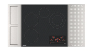 Black glass electric cooktop with four heating zones, touch controls, and integrated stainless steel side panels for kitchenware collections