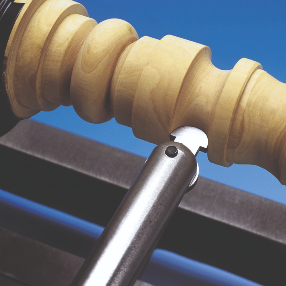 Close-up of hollowing tool tip carving precise grooves into light wood spindle for home improvement tasks