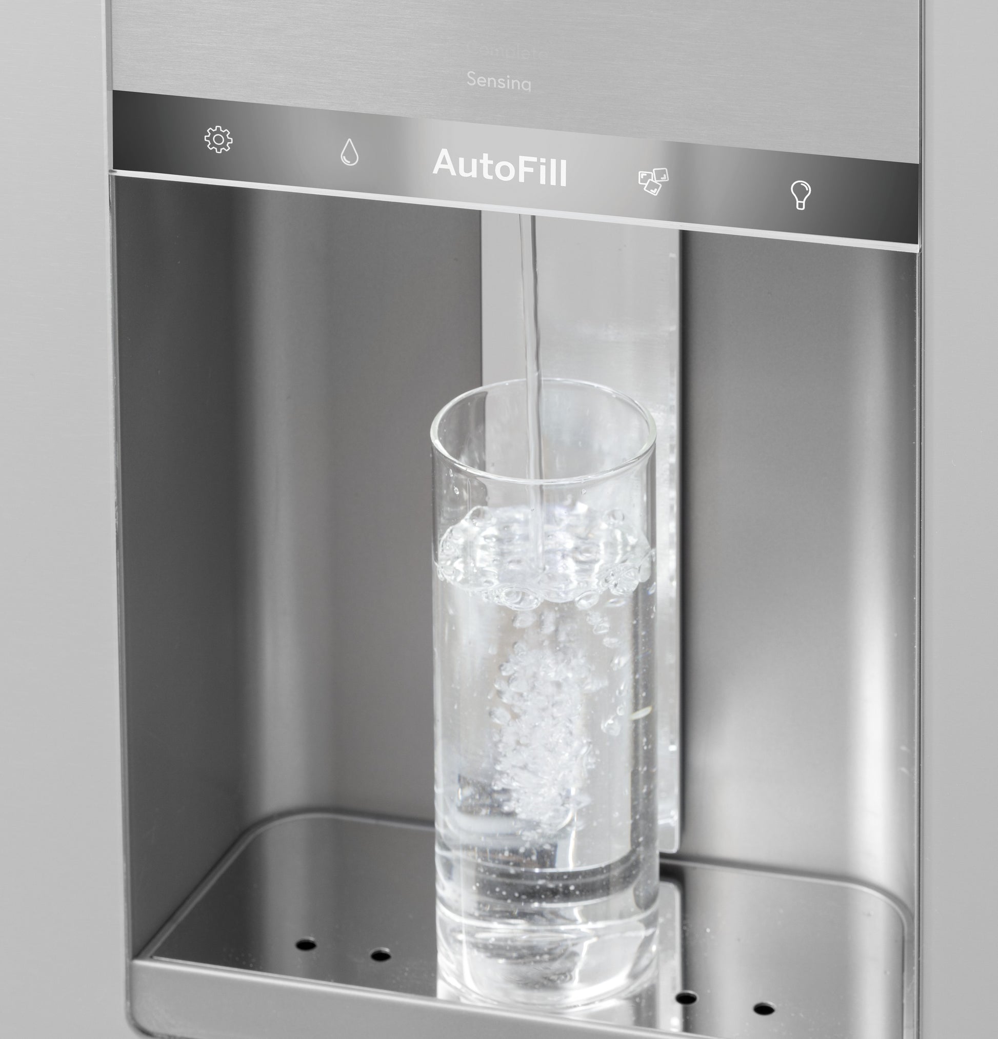 Close-up of stainless steel refrigerator water dispenser pouring water into a clear glass in kitchen appliances collection