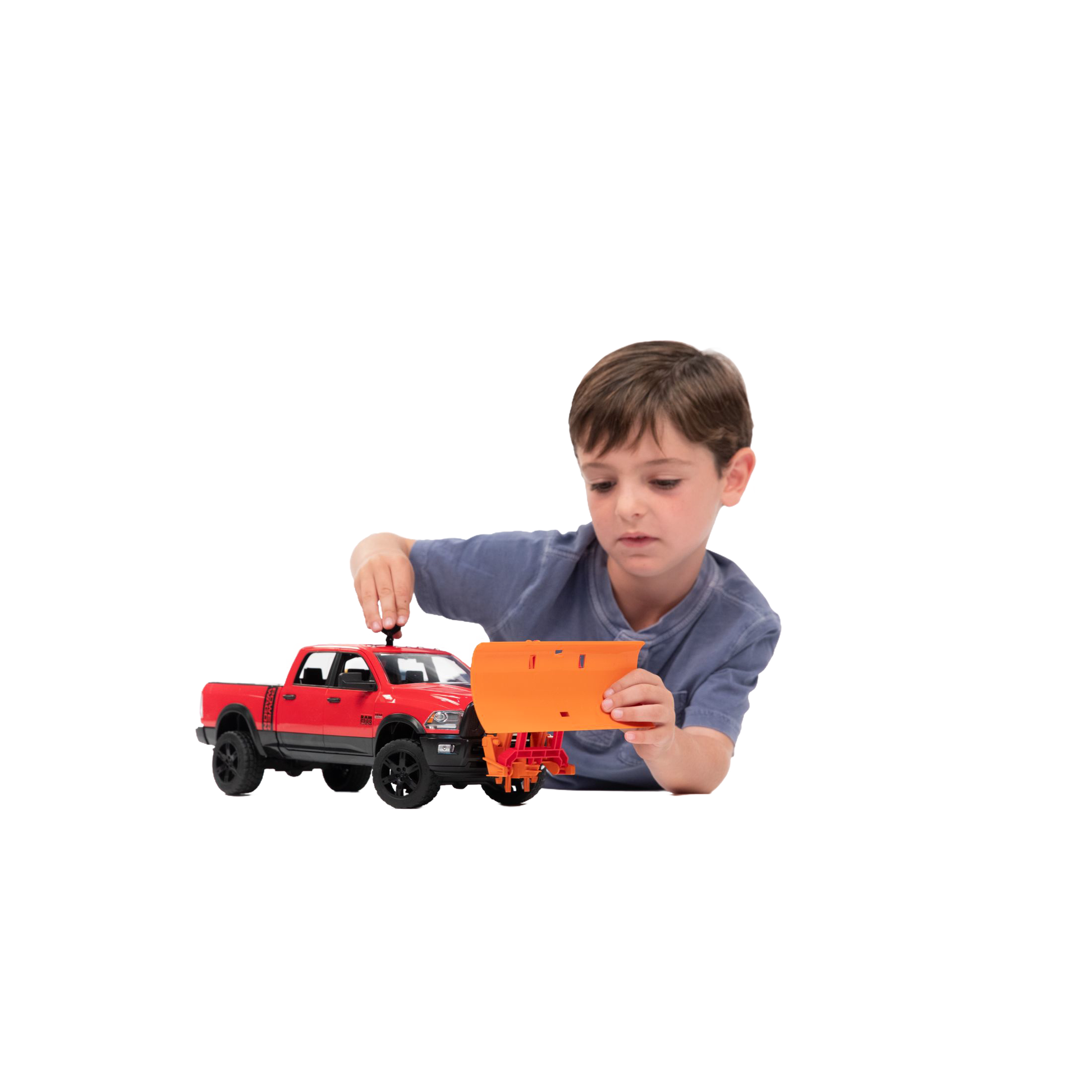 Young boy attaching an orange Bruder Toys plow blade to a red toy truck from Vehicles & Remote Controlled Toys collection