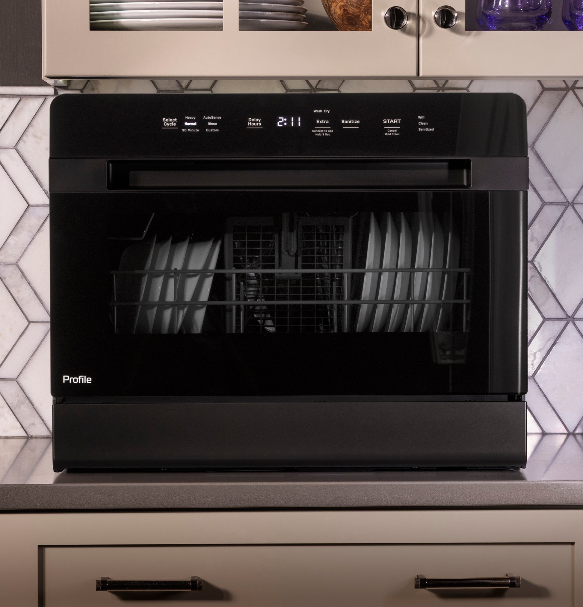 Black smart compact dishwasher with digital display and plates loaded inside on kitchen countertop surface