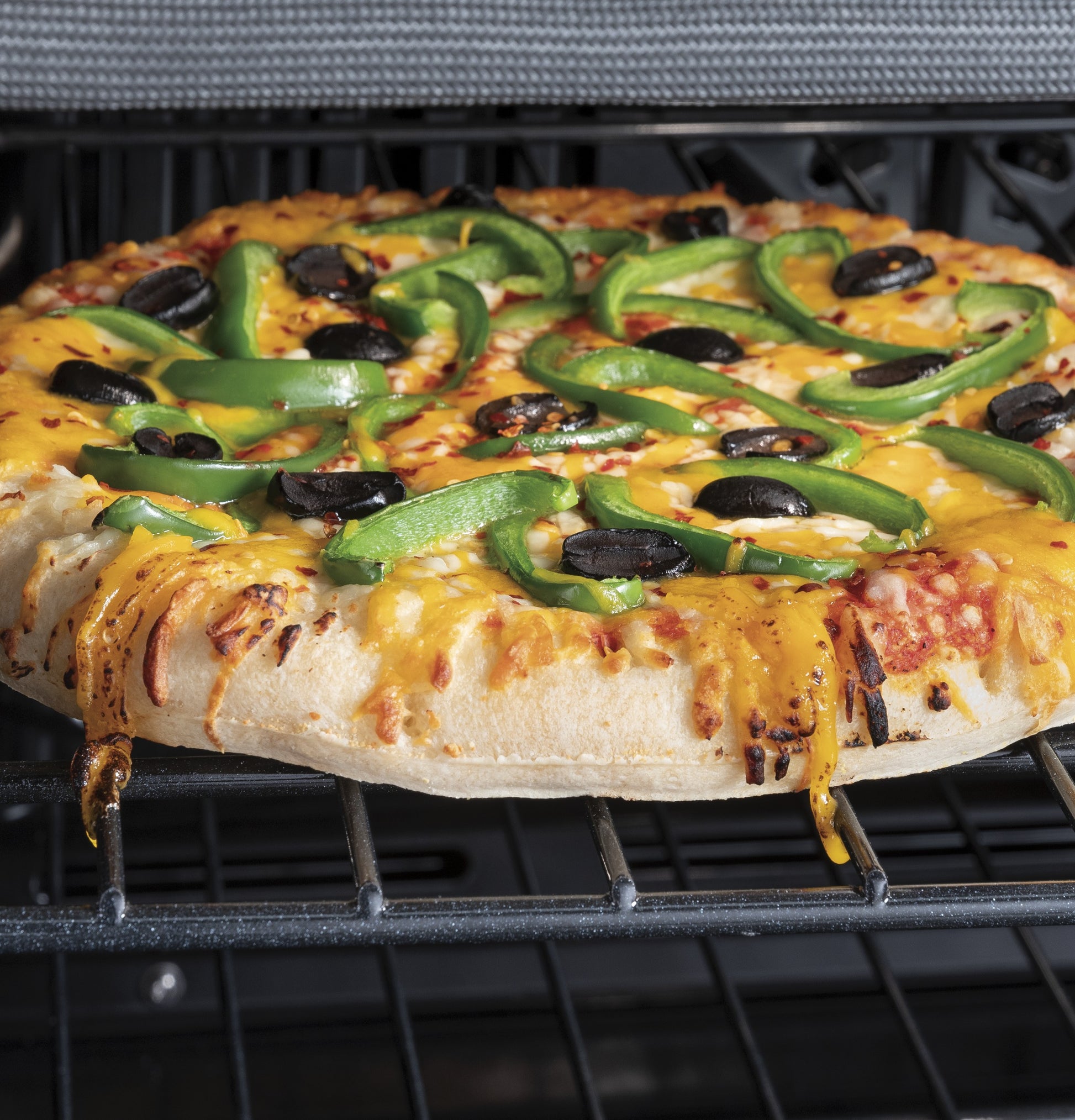 Close-up of fresh vegetable pizza baking inside a GE wall oven from the Kitchen & Kitchenware appliances collection