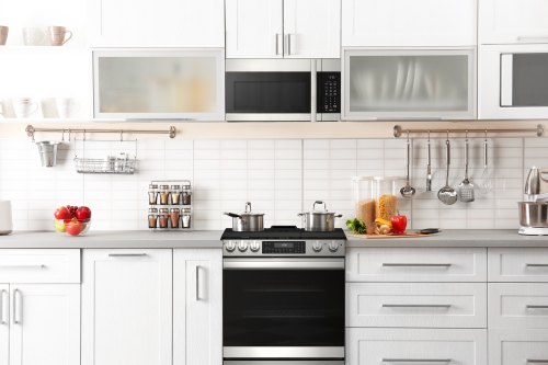 Modern kitchen setting featuring a sleek gas slide-in range with stainless steel accents in a white cabinetry kitchen collection
