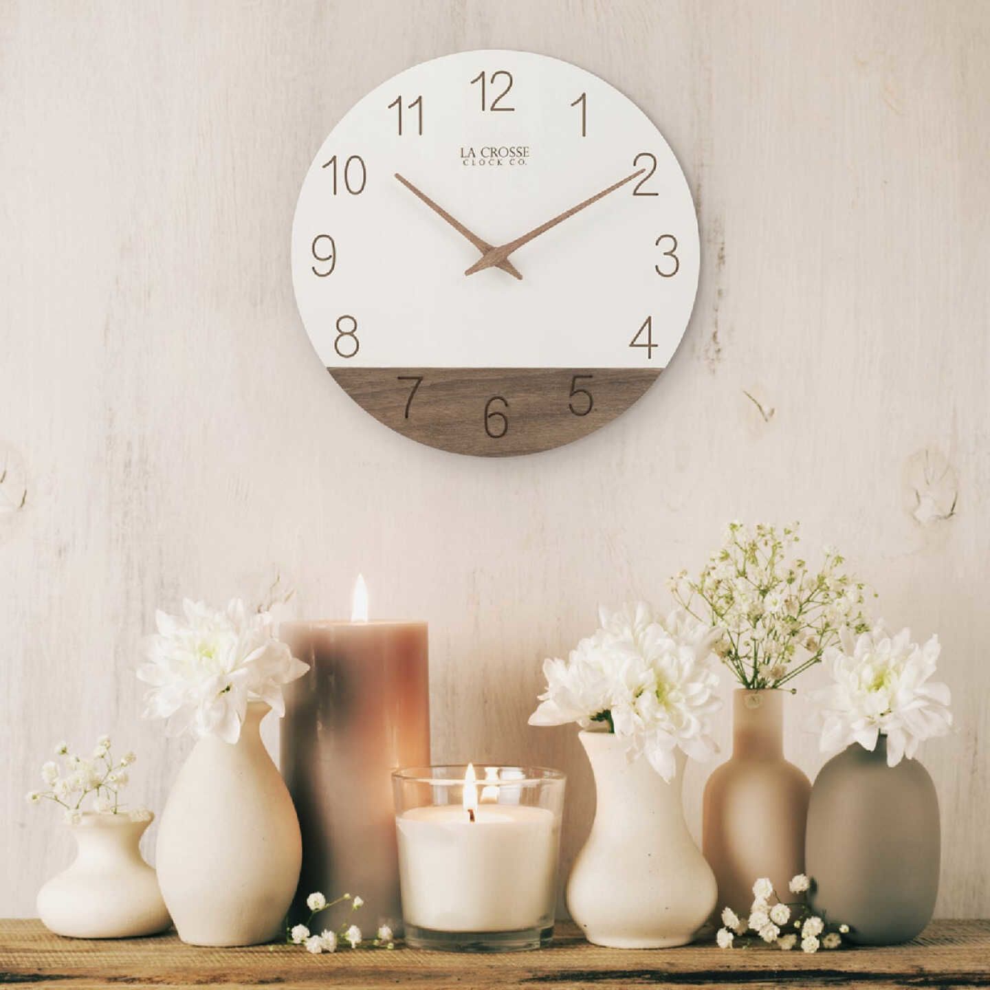 Wall clock with white vinyl dial, wood accent and brown laser engraved numbers, styled with neutral-toned home decor pieces