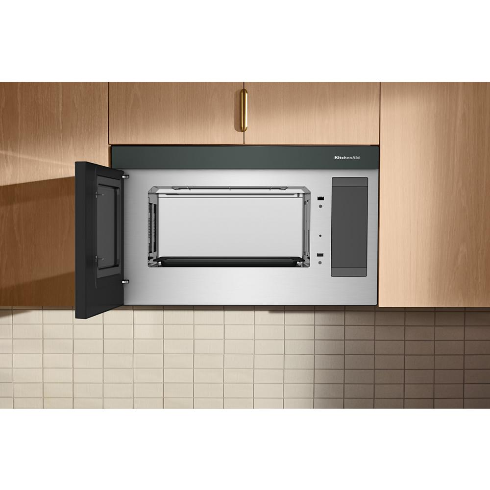 Sleek stainless steel multifunction over-the-range microwave oven with open door installed flush in light wood cabinetry