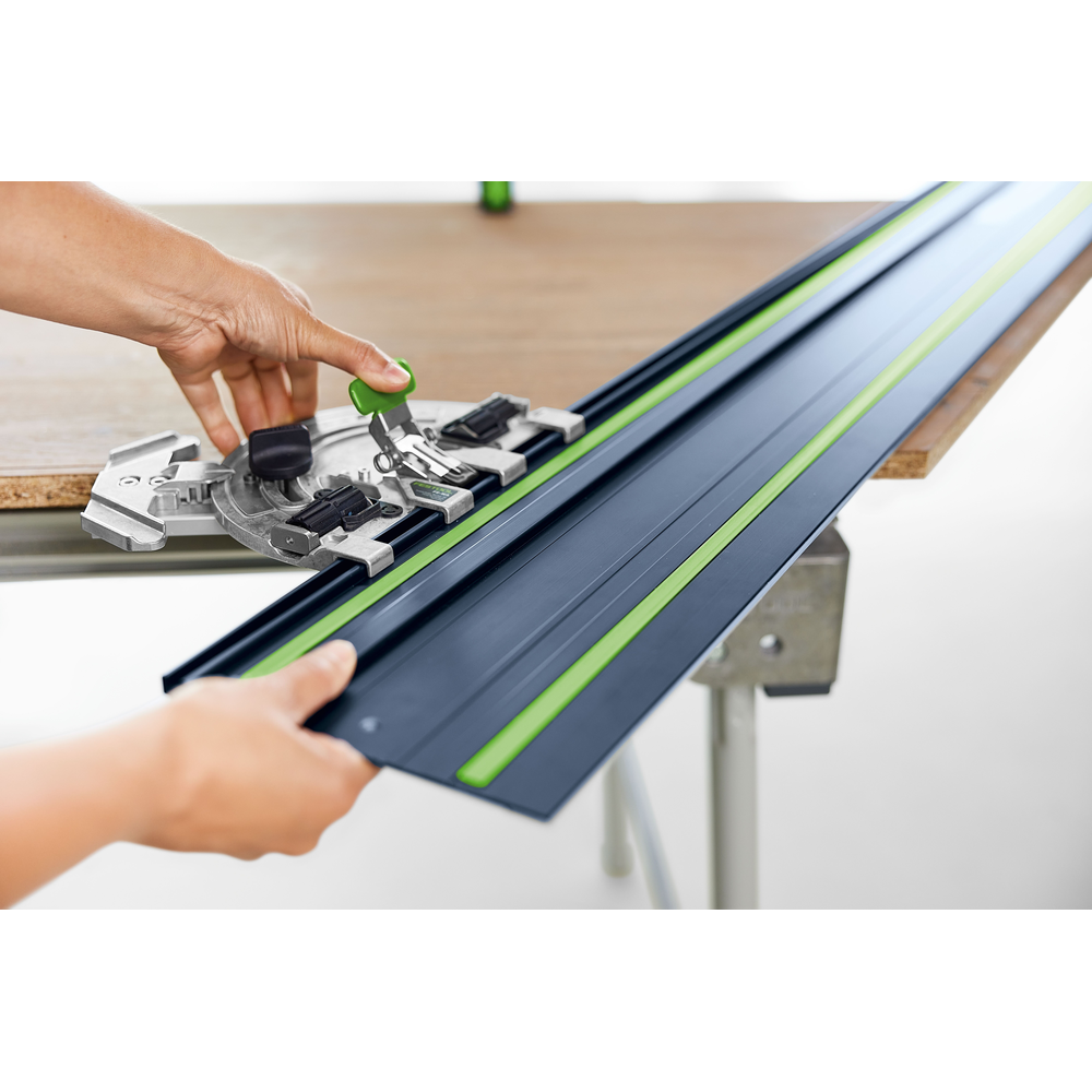 Hands adjusting a blue and green guide rail on a workbench for precise cuts in tools and home improvement projects
