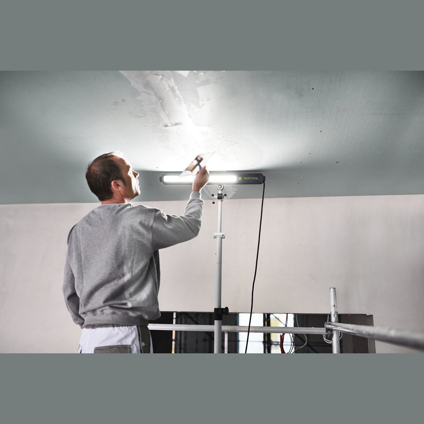 Professional surface control light mounted on tripod illuminating ceiling for detailed inspection in home improvement