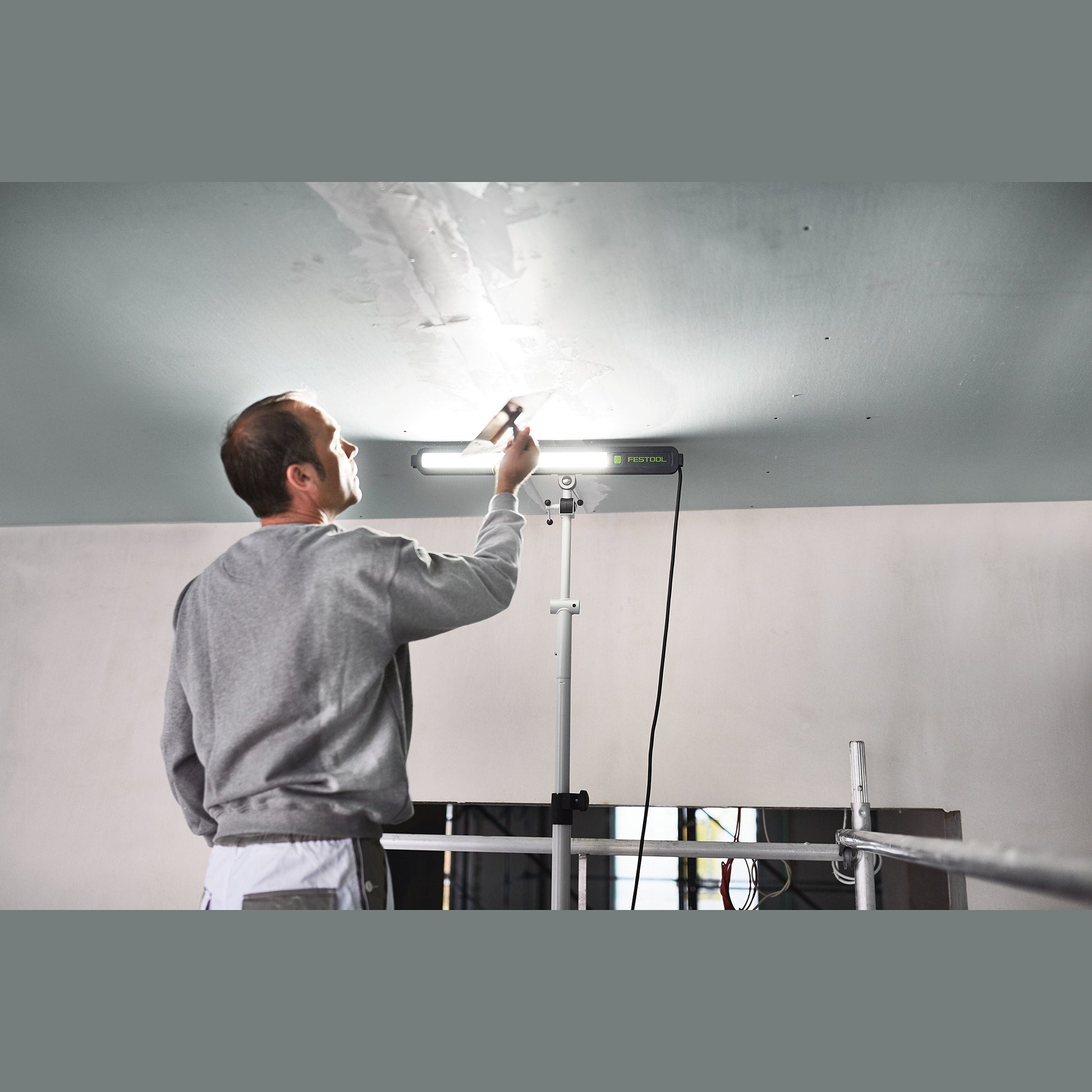 Professional surface control light mounted on tripod illuminating ceiling for detailed inspection in home improvement