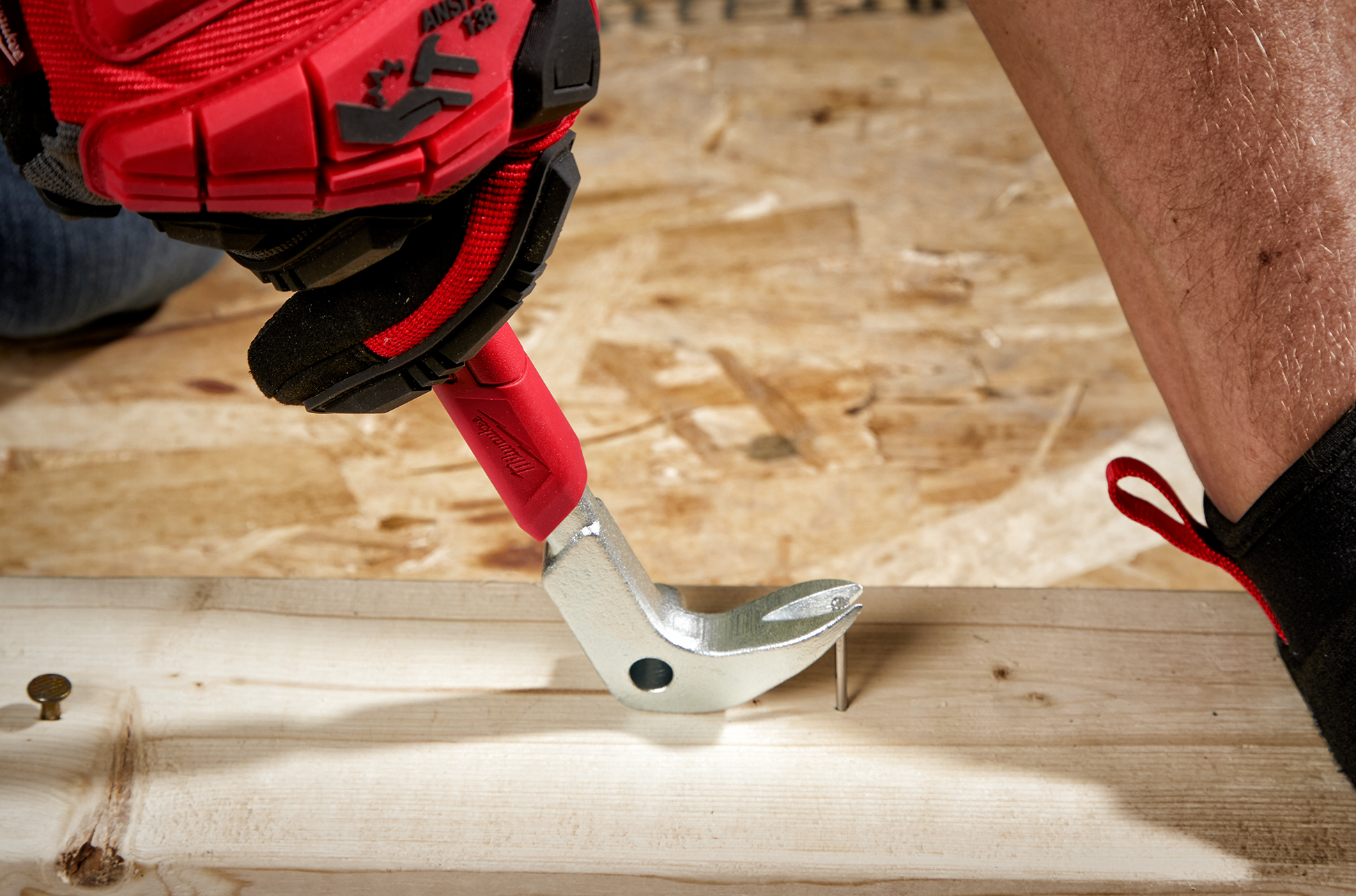 Red and silver finish nail puller prying a nail from wood during tools and home improvement work