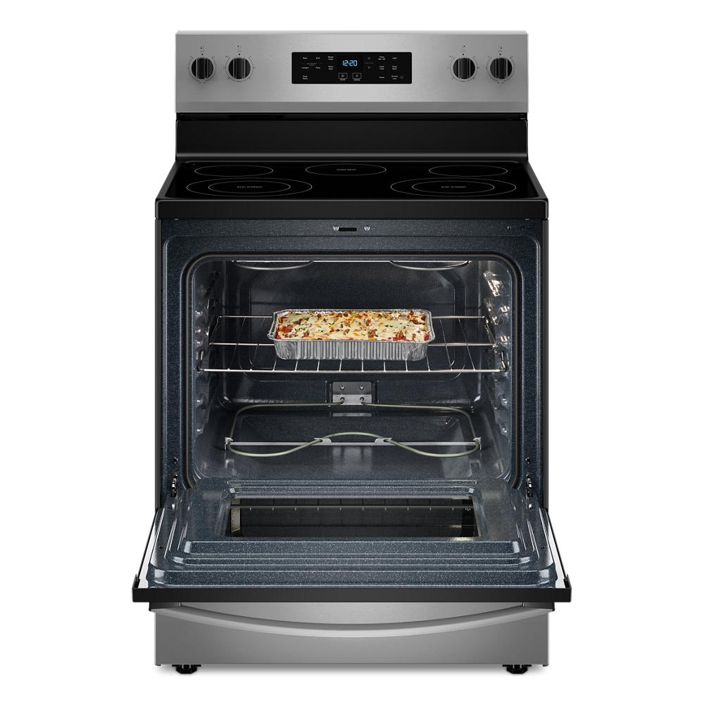 Open stainless steel electric range with smooth cooktop and baked casserole inside oven cavity in kitchen setting