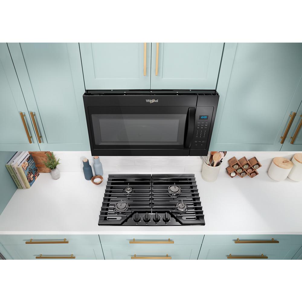 Black over-the-range microwave with electronic touch controls mounted above gas cooktop in modern kitchen setting
