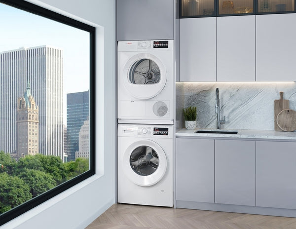 Stacked white Bosch compact condensation dryer and washer next to gray cabinetry in modern laundry space with city view