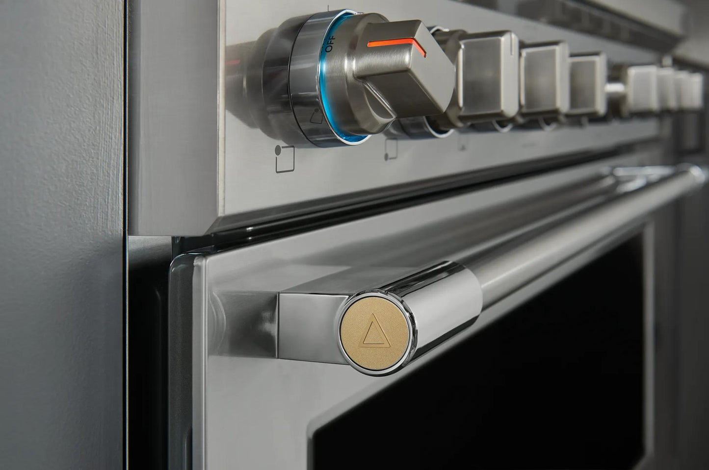 Close-up of stainless steel oven door handle and control knobs on a 36-inch dual-fuel range in kitchen appliances collection