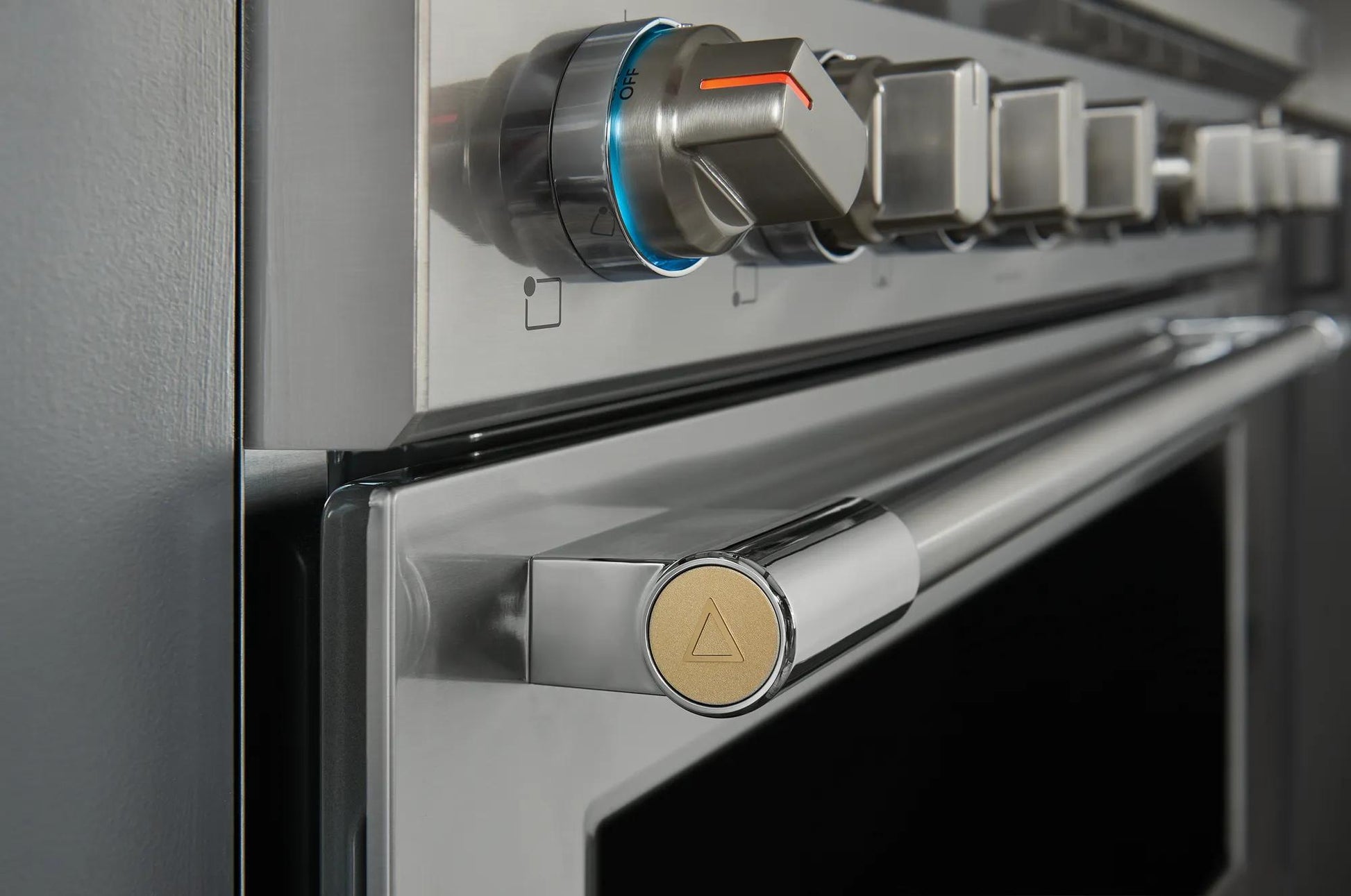 Close-up of stainless steel oven door handle and control knobs on a 36-inch dual-fuel range in kitchen appliances collection