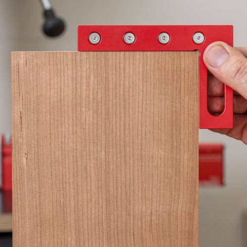 Red anodized multi-marking square held against wood for precise joinery layouts in woodworking hand and measuring tools collections
