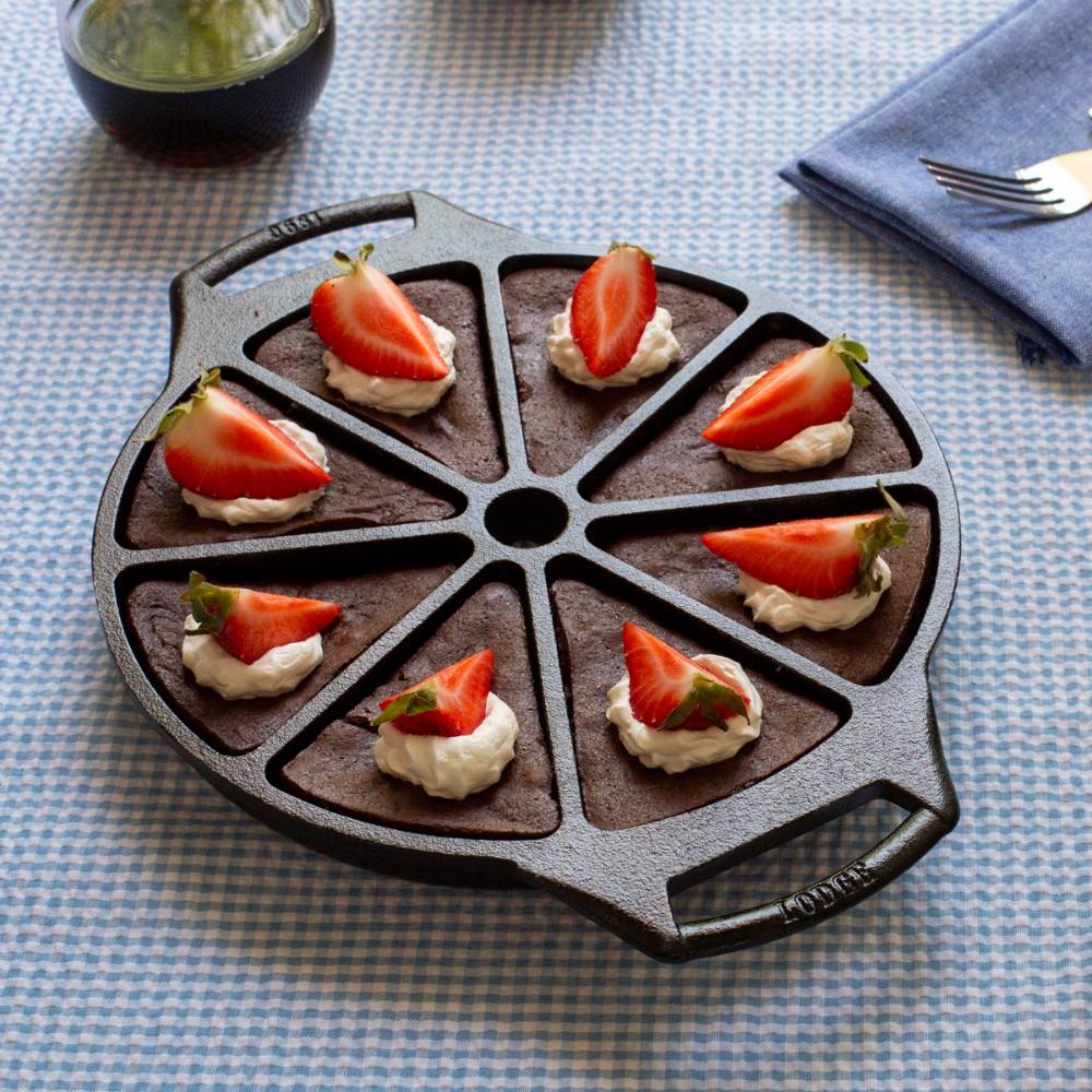 Cast iron wedge pan with eight triangular sections filled with chocolate desserts topped with cream and strawberry halves