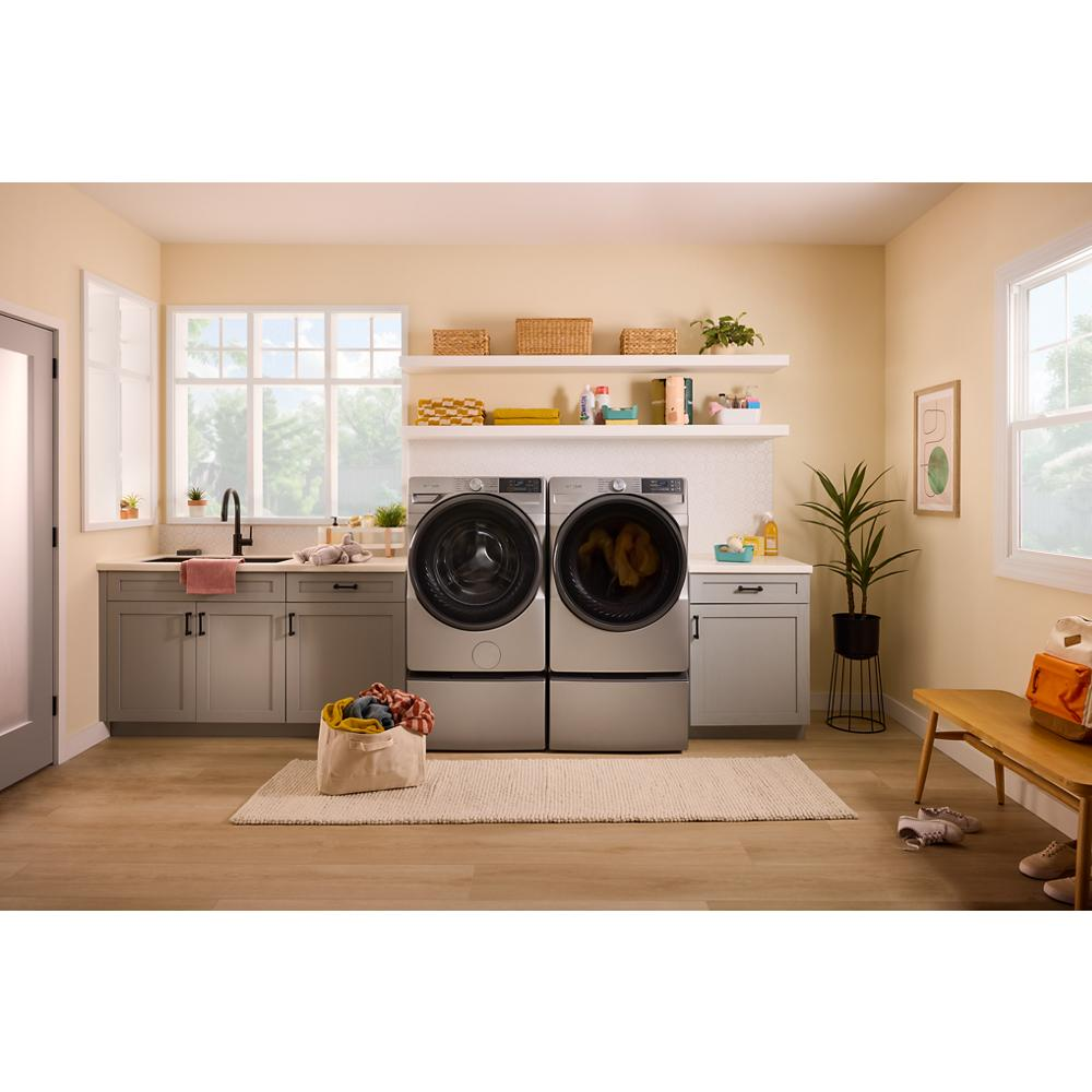 Modern laundry room with front load washer and dryer pair in gray cabinets and natural light from large windows