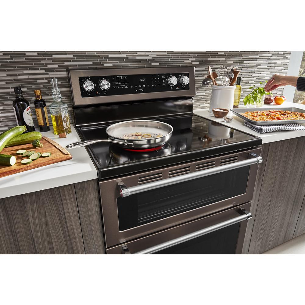 Electric double oven convection range with five burners cooking in modern kitchen with tools and ingredients nearby