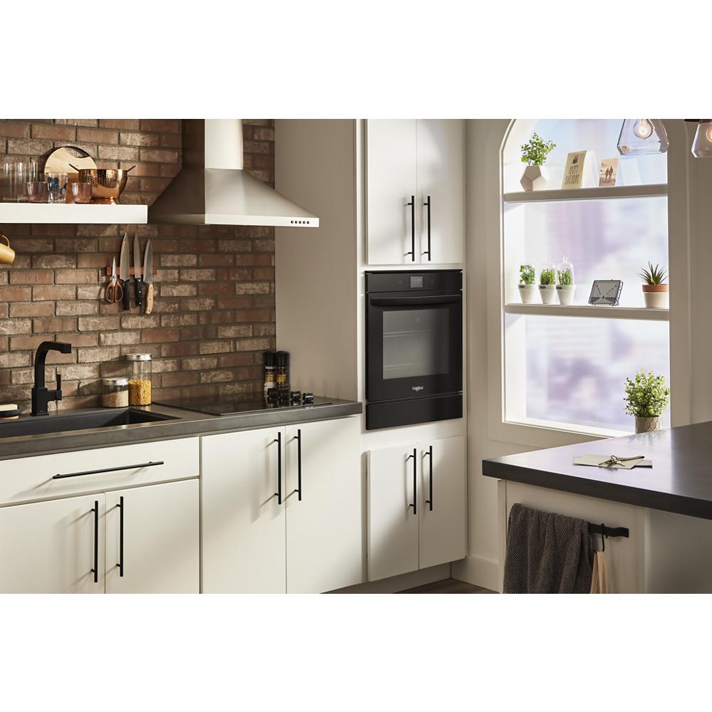 Black built-in double wall oven with convection cooking integrated into white kitchen cabinetry with brick backsplash and modern fixtures